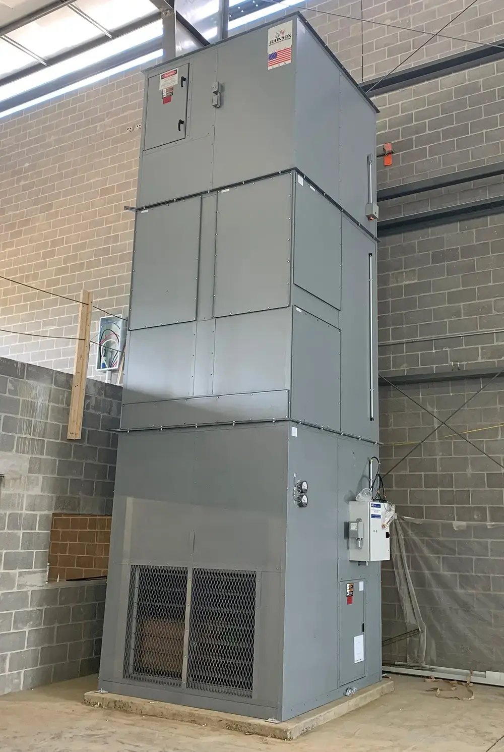 Large industrial HVAC unit installed inside a building with exposed brick walls